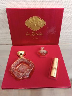 une boîte rouge contenant un flacon de parfum et un rouge à lèvres
