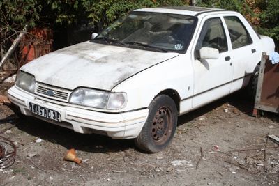 a white car that is parked in the dirt