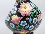 a black vase with colorful flowers on it on a clear stand