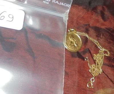 un collier en or avec une chaîne posé sur un tissu rouge