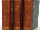 trois vieux livres posés l'un sur l'autre sur une surface blanche