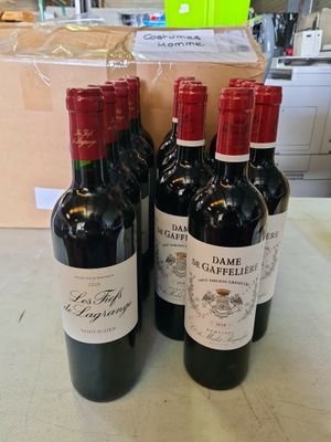 trois bouteilles de vin rouge posées sur un plan de travail, à côté d'un carton