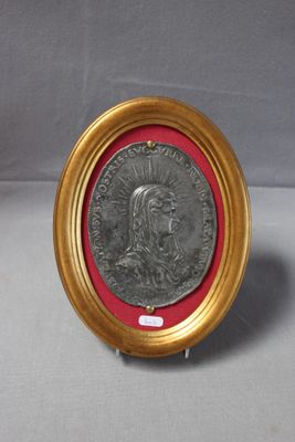 une vieille médaille en argent dans un cadre doré bordé de rouge