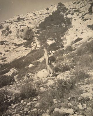 a black and white photo of a man standing on a rocky hill