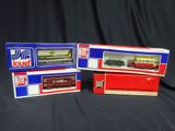 trois boîtes contenant des trains miniatures, posées sur une surface noire
