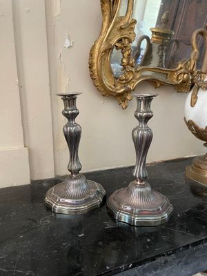 deux vases en argent posés sur une table à côté d'un miroir