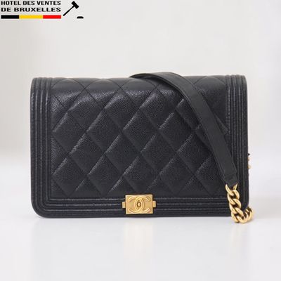 un sac Chanel noir muni d'une chaîne dorée sur fond blanc