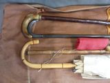 three old canes and an umbrella sitting on a bag