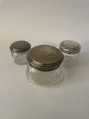 trois bocaux en verre avec des couvercles argentés posés sur une table