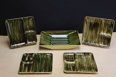 quatre assiettes et plateaux verts et blancs posés sur une table