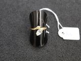 une bague noire et dorée posée sur une surface noire, avec une étiquette de prix