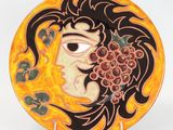 assiette jaune et noire ornée d'un visage de femme et de raisins