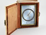 une petite horloge à l'intérieur d'une boîte en bois posée sur une surface blanche