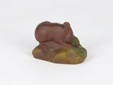 figurine of a bear sitting on a rock on a white surface
