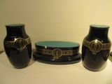 three black vases sitting on a table with a blue plate