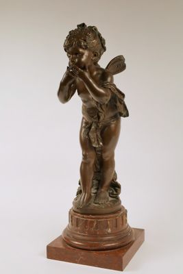 an antique bronze statue of a boy playing a flute