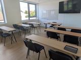des tables et des chaises dans une salle de classe, avec un téléviseur à écran plat accroché au mur
