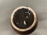 a brown and white bowl with a black substance in it