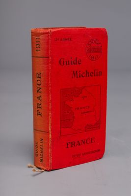 un livre rouge posé sur une table à côté d'un mur blanc