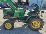 a green tractor with yellow wheels parked in a parking lot