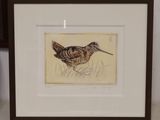 tableau représentant un oiseau, encadré, posé sur une table à côté d'un vase