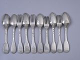 six spoons and a fork are lined up on a table