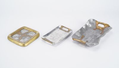 two pieces of silver and gold metal on a white surface