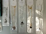 five different necklaces hanging on a wall in a row