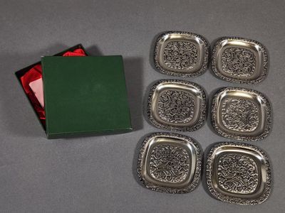six silver trays and a green box on a table