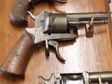 two old revolvers on a wooden table next to each other