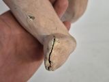 a hand holding a wooden doll with a broken leg