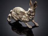 une figurine de lapin en argent posée sur une surface noire
