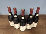six bottles of wine are lined up on a wooden table