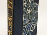 an old book with a blue cover sitting on a white surface