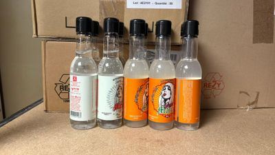 quatre bouteilles d'alcool posées sur une table à côté d'un carton