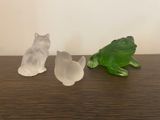 trois figurines représentant des chats et une grenouille posées sur une table