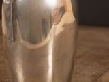 a silver vase sitting on a wooden table with a black background