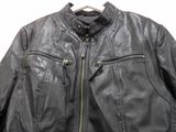 black leather jacket with zippers on a hanger on a white wall