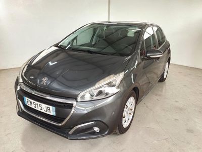 La voiture grise est garée dans une grande pièce aux murs blancs.