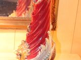 a red and white vase sitting on a table in front of a mirror