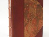 an old book with a red cover sitting on top of a white surface