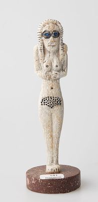 statue d'une femme portant des lunettes de soleil sur la tête, posée sur un socle en bois