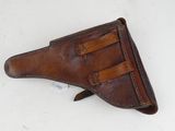a brown leather holster with two leather straps on a white surface