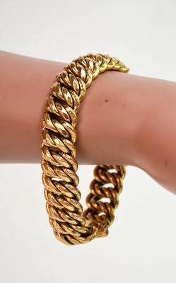 un gros plan sur la main d'une personne portant un bracelet en or