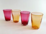 four different colored glasses are lined up on a white surface