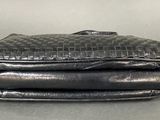 two black leather bags stacked on top of each other on a table