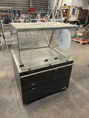 une vitrine avec un couvercle en verre, au milieu d'un entrepôt