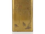 an image of a gold lighter with a bird and tree design on it