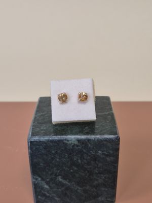 une paire de boucles d'oreilles en or posée sur un bloc de marbre