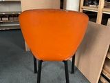 an orange chair with black legs in a room